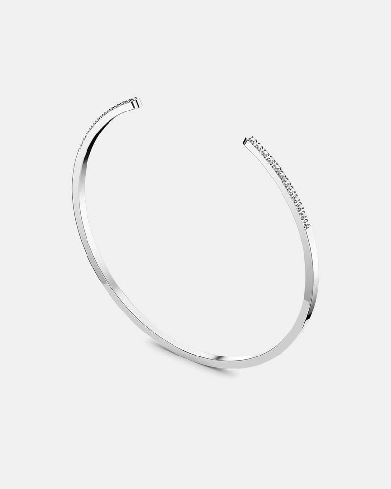 A polished stainless steel bangle in silver from Waldor & Co. One size. The model is Acme Bangle Polished