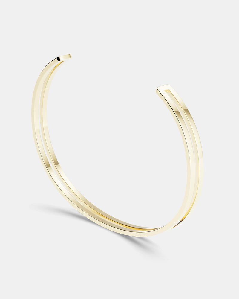 A polished stainless steel bangle in 14k gold from Waldor & Co. One size. The model is Dual Bangle Polished. 